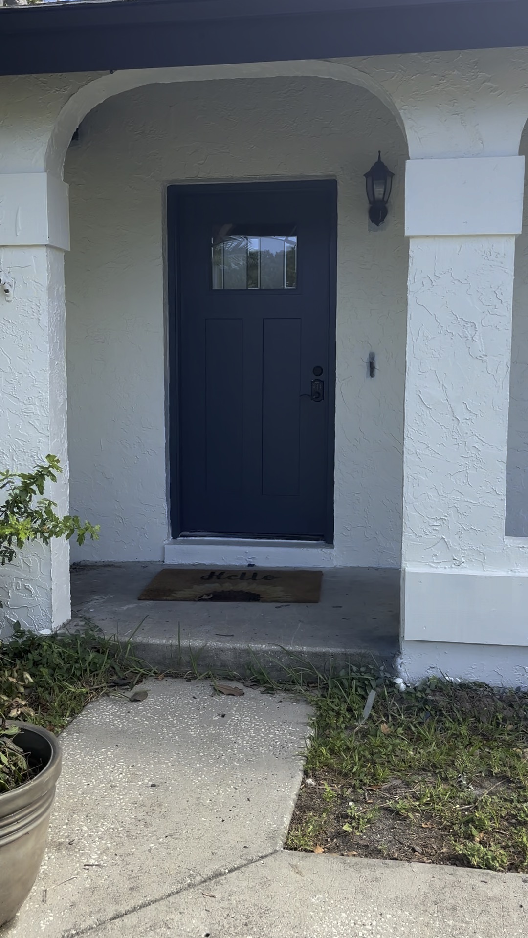 House exterior after — crisp white stucco with a fresh navy entry door