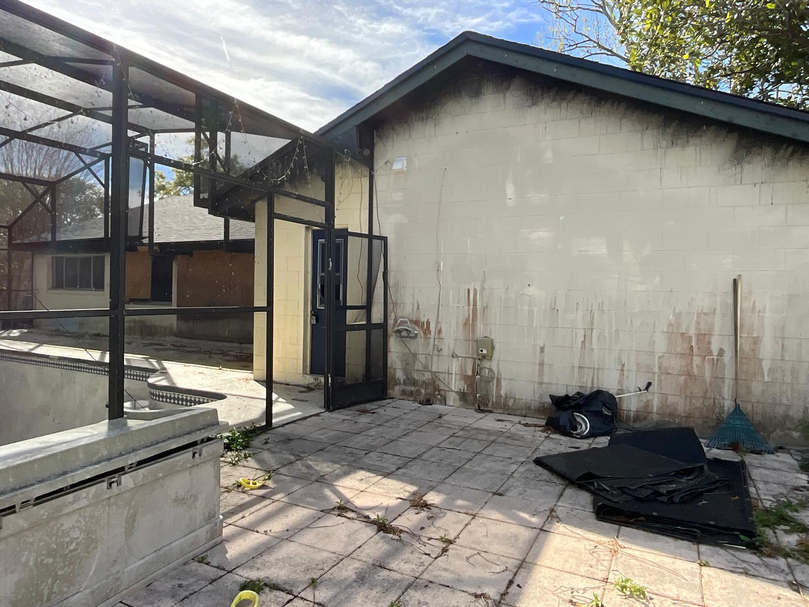 House exterior before — mildew-stained, weathered block wall