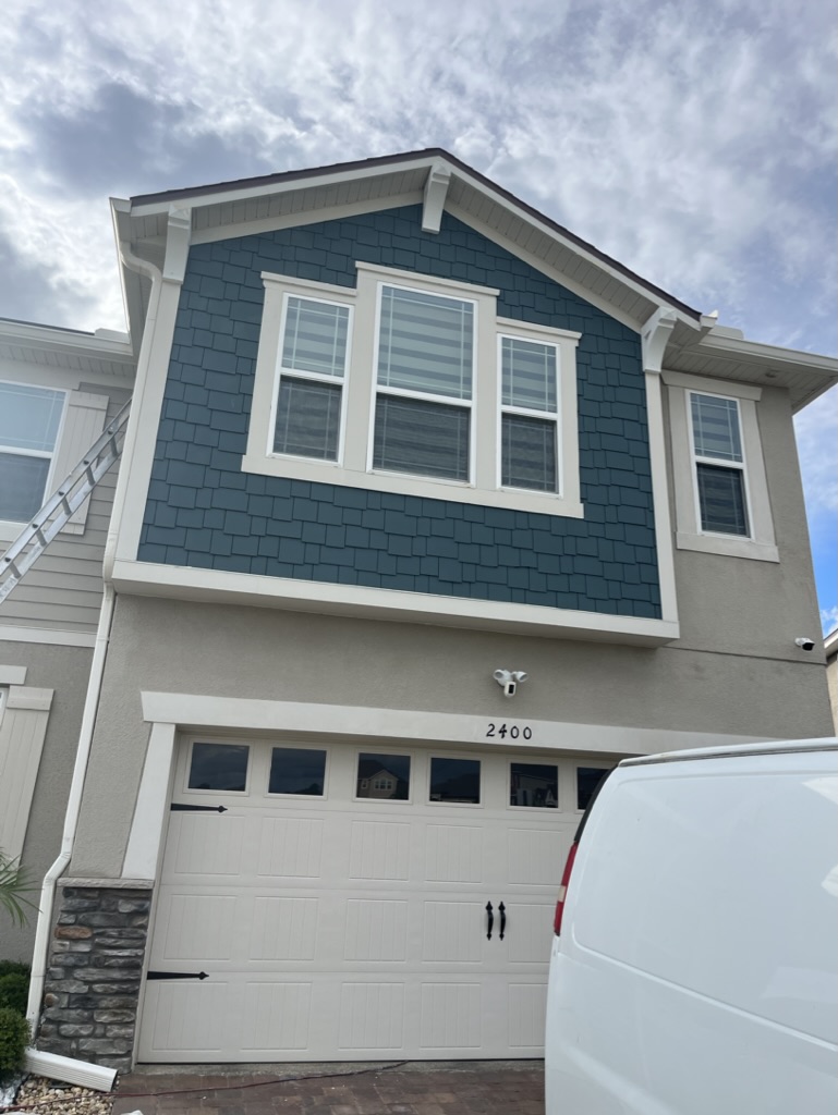 Two-story home with a freshly painted teal gable and trim