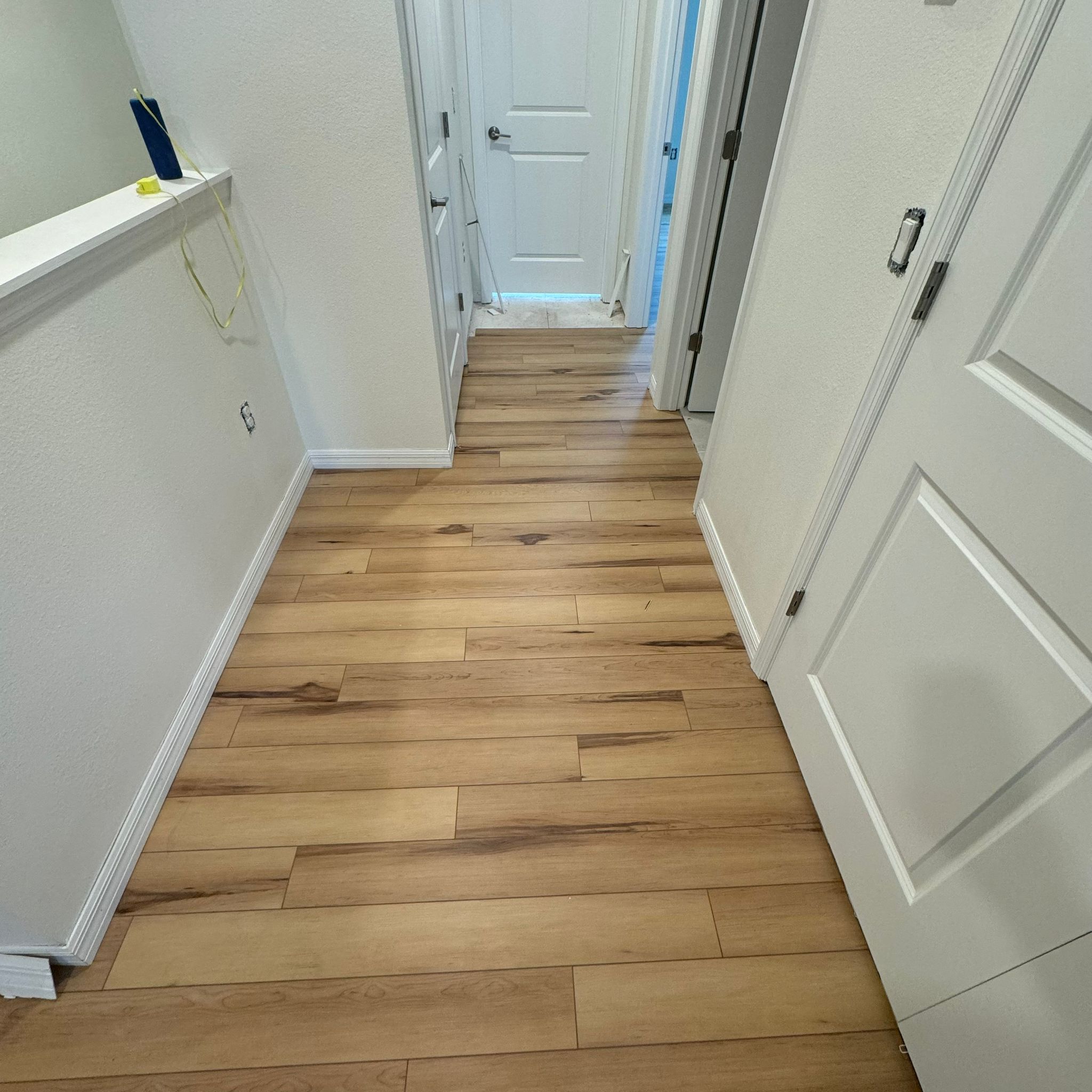 Bright hallway with freshly painted walls, doors, and trim over wood floors